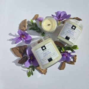 Savvy Saffron 16 oz flatlay candles on a whtie background surrounded by saffron flowers, wood pieces, and greenery