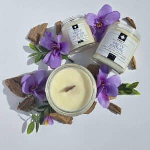 Savvy Saffron 16 oz flatlay candles on a whtie background surrounded by saffron flowers, wood pieces, and greenery