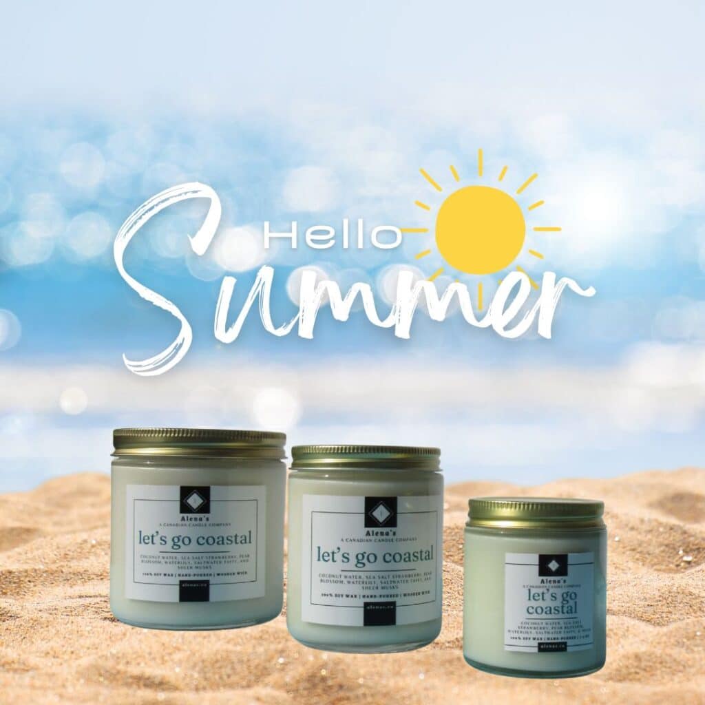 Alena’s Let’s Go Coastal soy wax candle with wooden wick in gold jar, styled with seashells, ocean elements, and summer sunlight