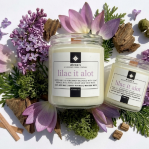 wooden wick candle on a white background with moss, cedar wood, lilacs, and waterlily petals surrounding it